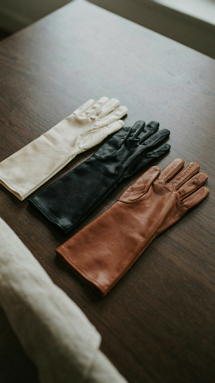 Various long gloves made of silk, satin, and leather on a table.