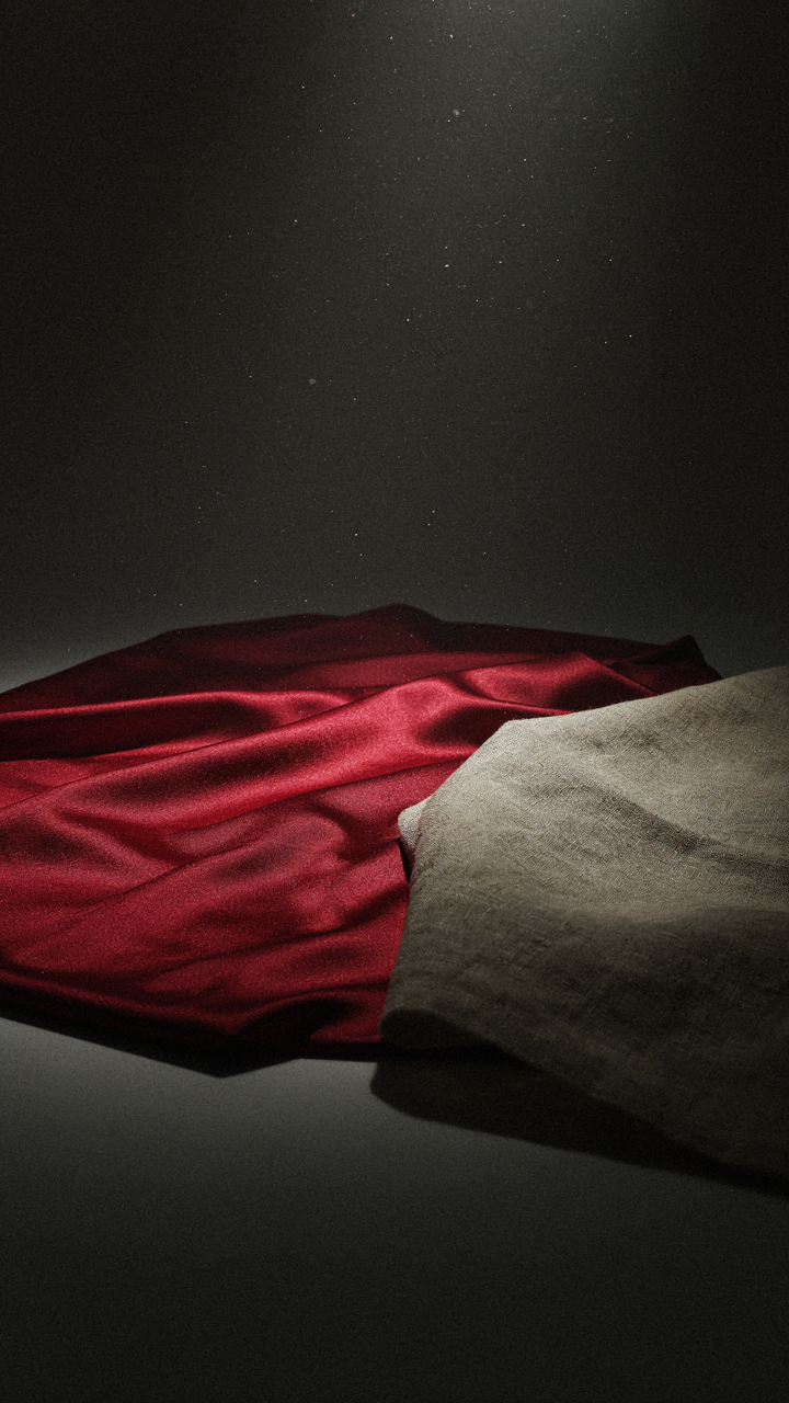 Spotlight on red satin, contrasting its smooth reflection with rough linen.