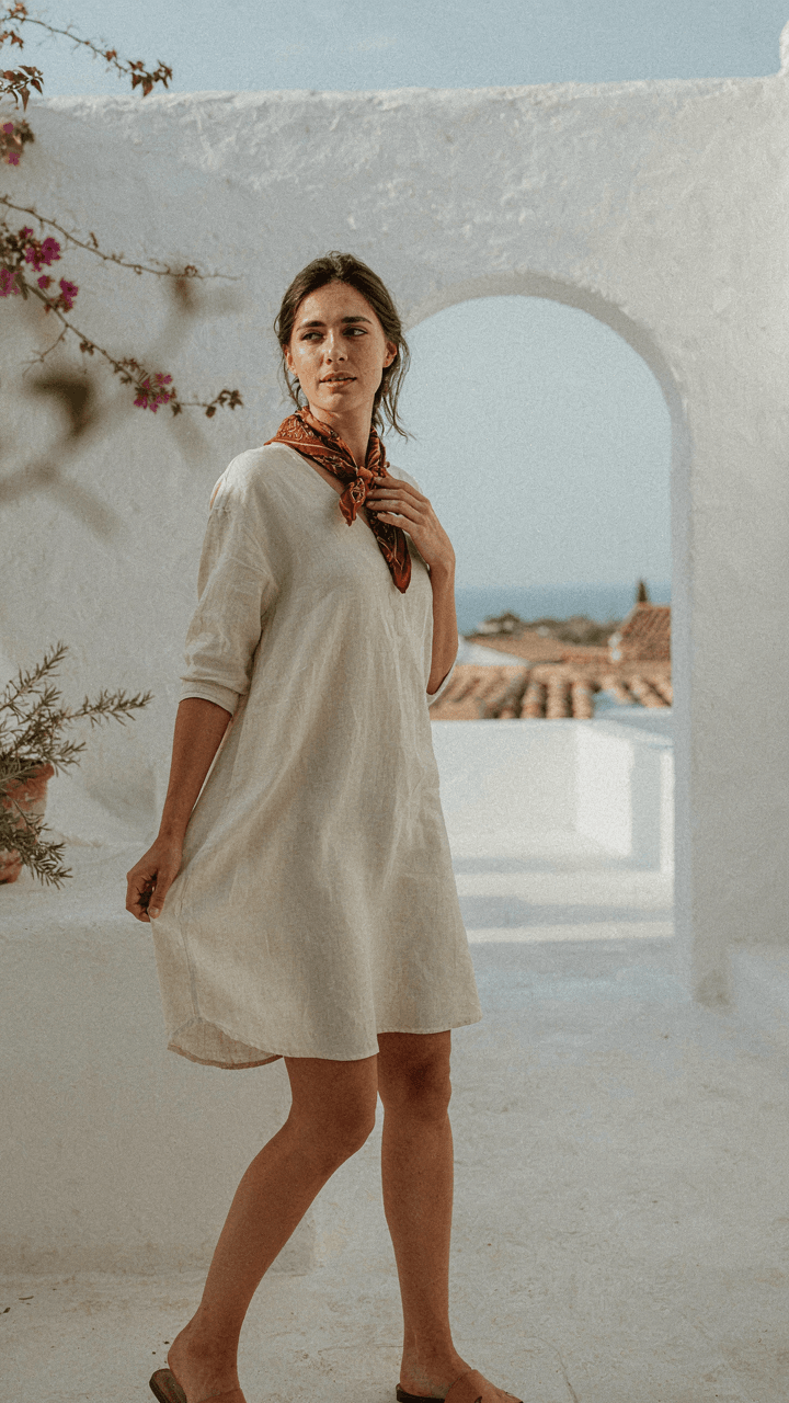 A woman in a linen shift dress and silk scarf outdoors.