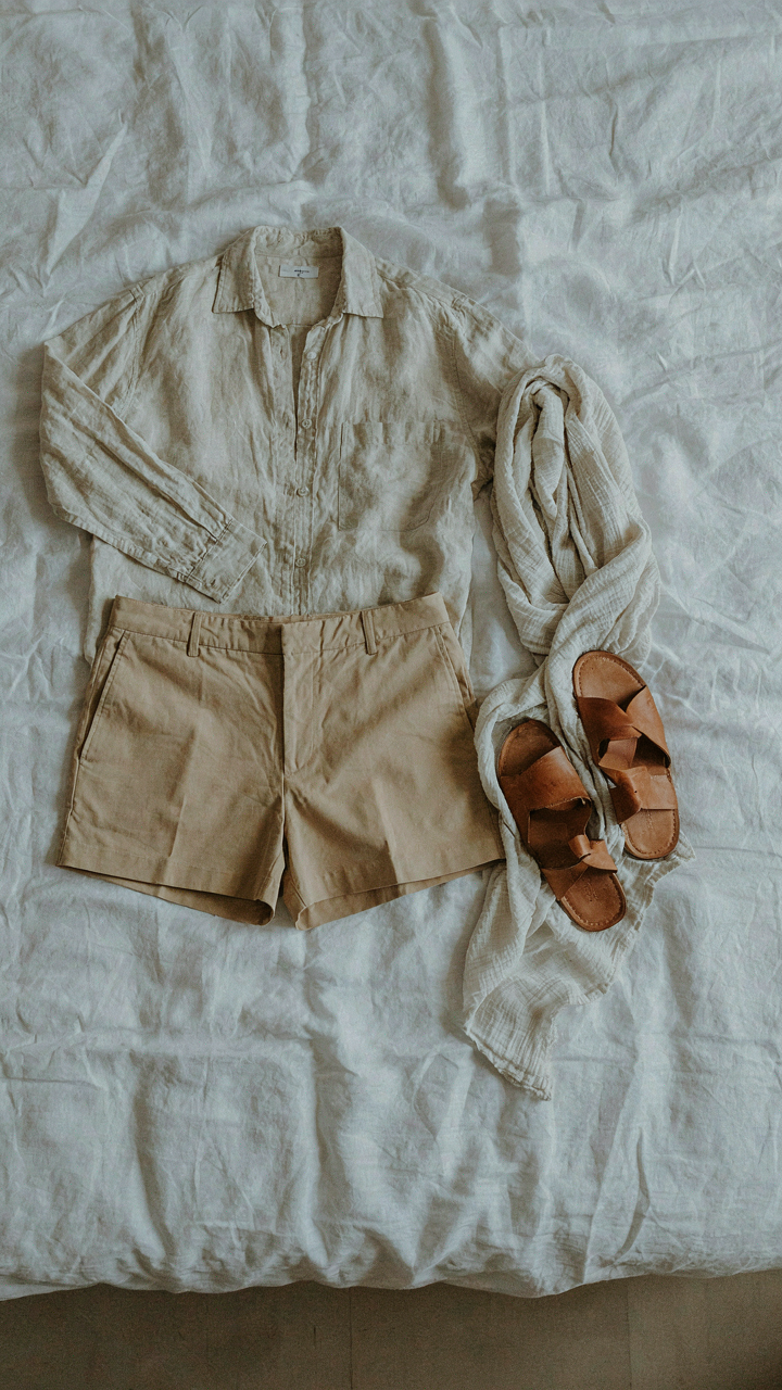 Minimalist travel capsule wardrobe with a linen shirt, shorts, wrap, and sandals.