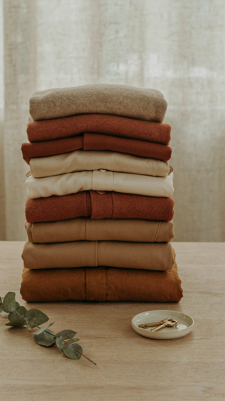 A neat stack of color-coordinated clothes in warm, earthy tones.