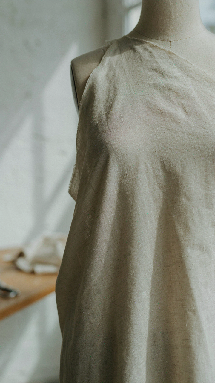 Close-up of a bias-cut linen fabric on a mannequin, showing its specific weave and texture.