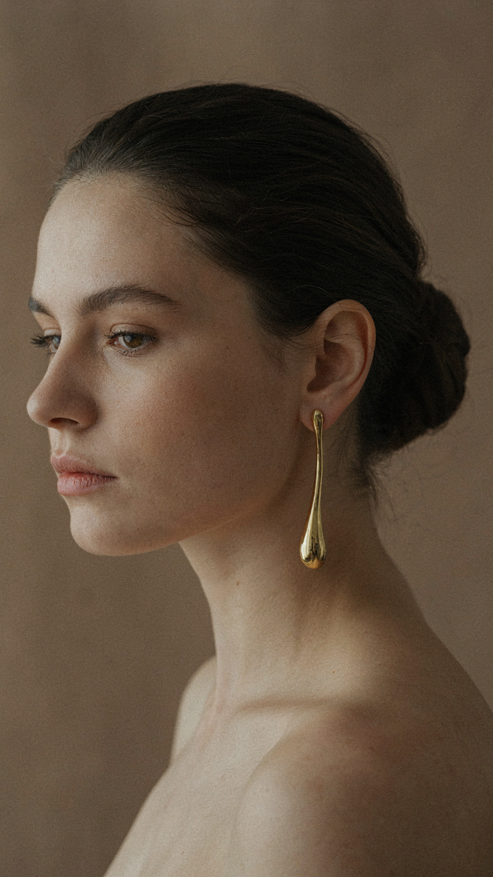 A model wears a single, long statement earring on one ear.