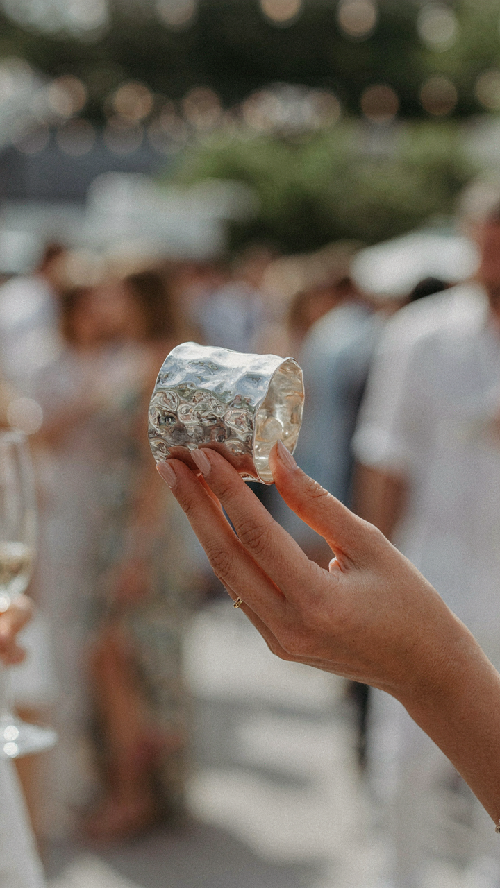 A hand holds a striking piece of sculptural jewelry at an event.
