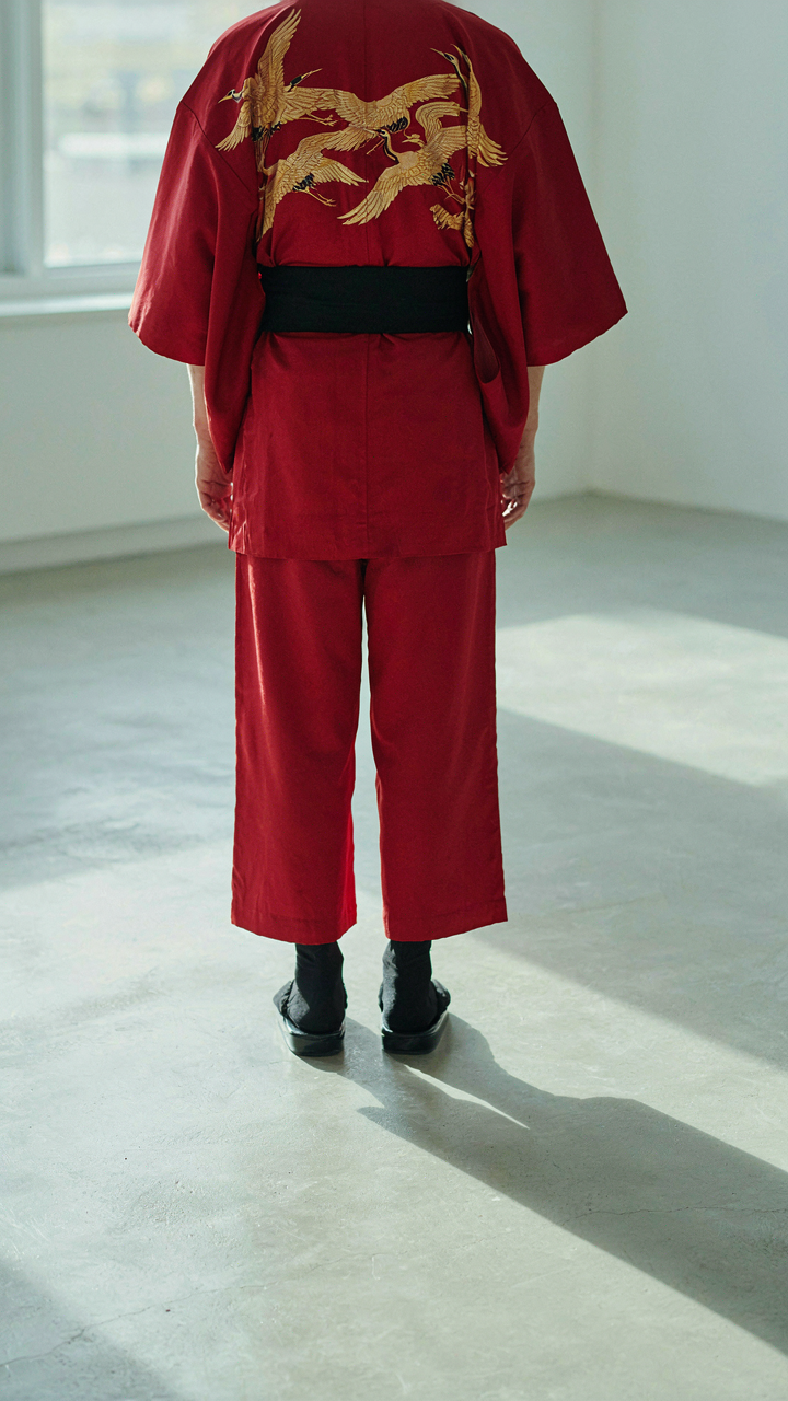 A person wearing a striking kimono jacket stands confidently, casting a long shadow.