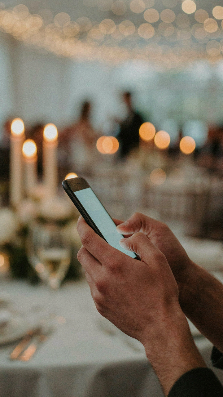 A hand holds a smartphone, texting, with a blurred elegant background.