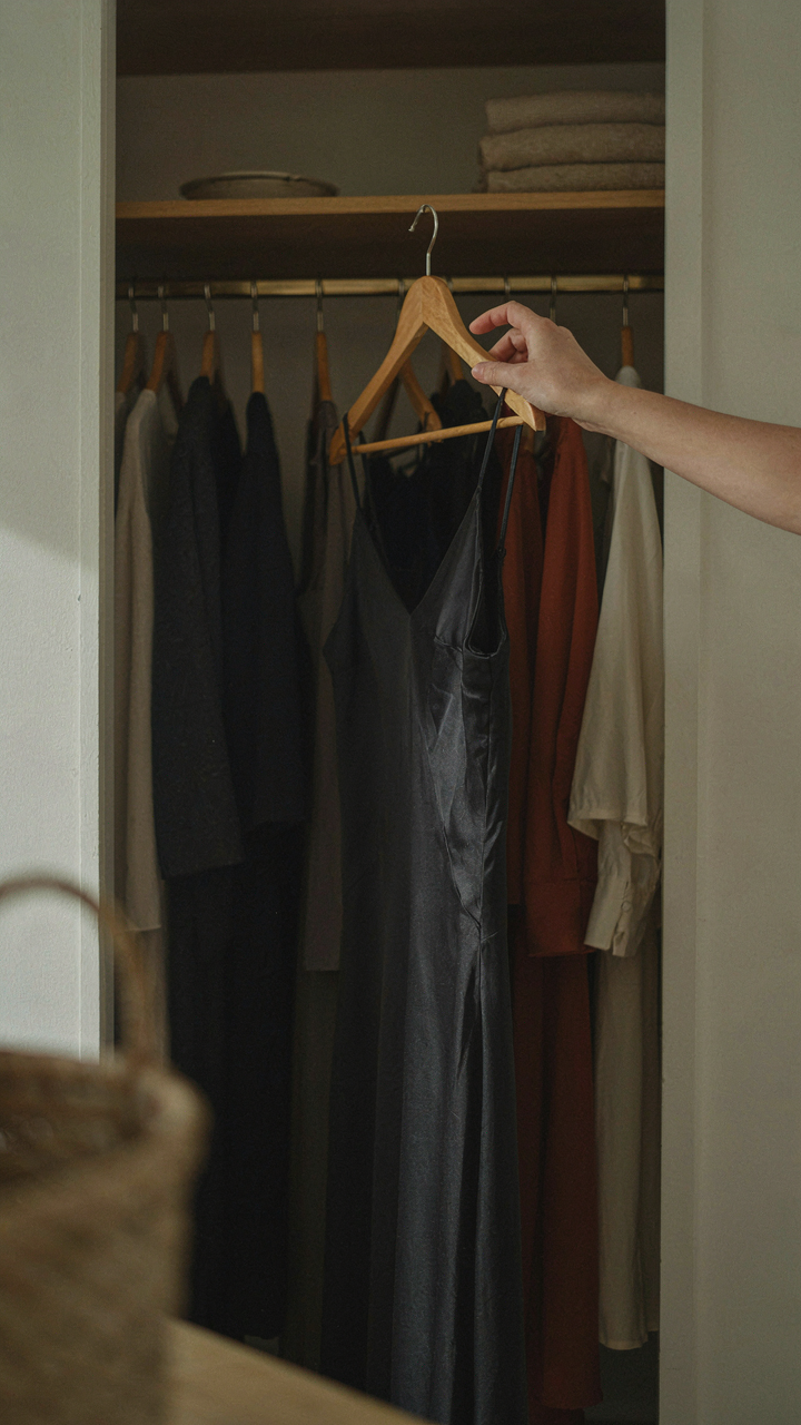 A woman's hand picks out a single elegant black garment.