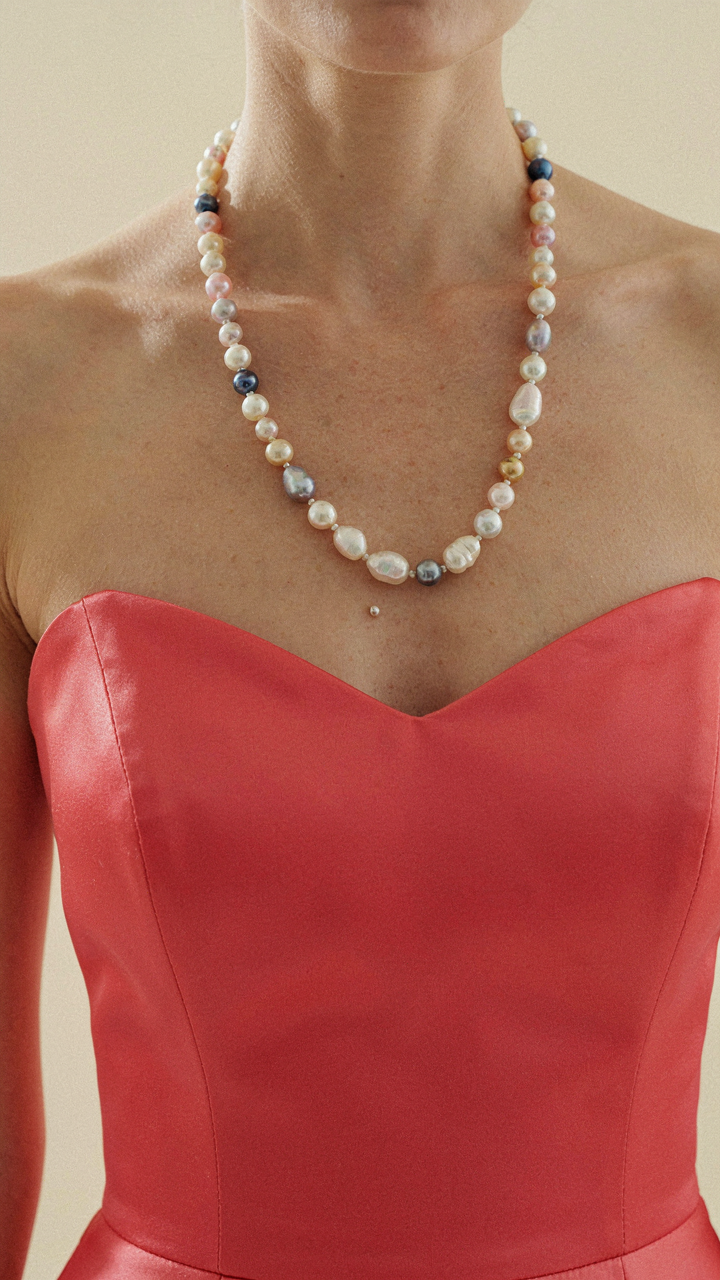 A colorful cocktail dress has an intentionally mismatched pearl necklace.