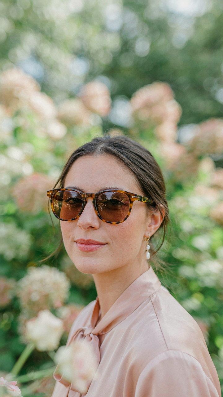 A guest's face framed by classic tortoiseshell sunglasses that match their outfit.