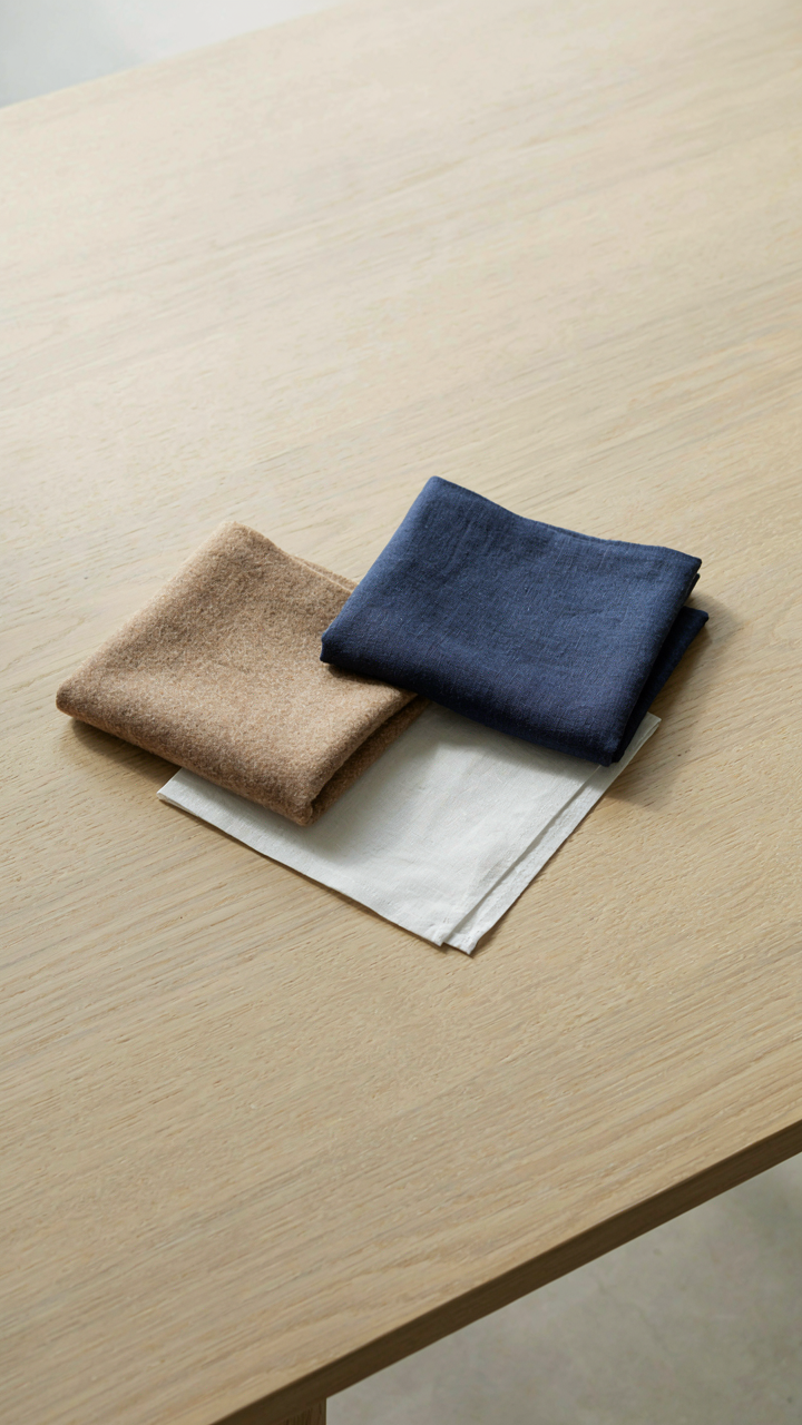 Three fabric swatches, camel, navy, and white, are arranged neatly on a table.