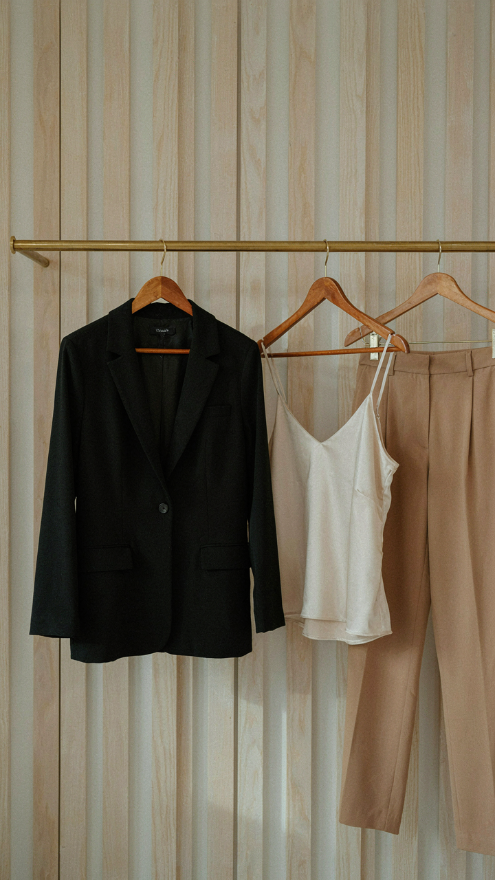A closet with a tailored black blazer, silk camisole, and high-waisted trousers.