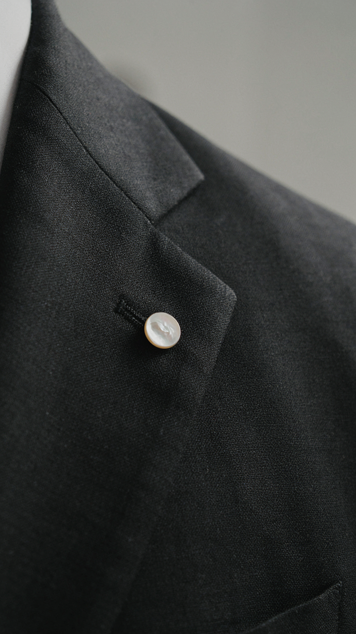 Close-up of a dark, tailored suit jacket lapel made from gabardine fabric.