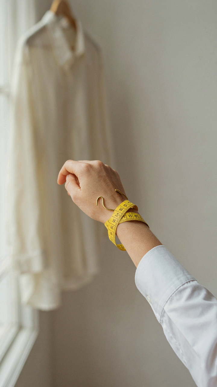 A measuring tape at a woman's wrist, showing a perfectly fitting sleeve.