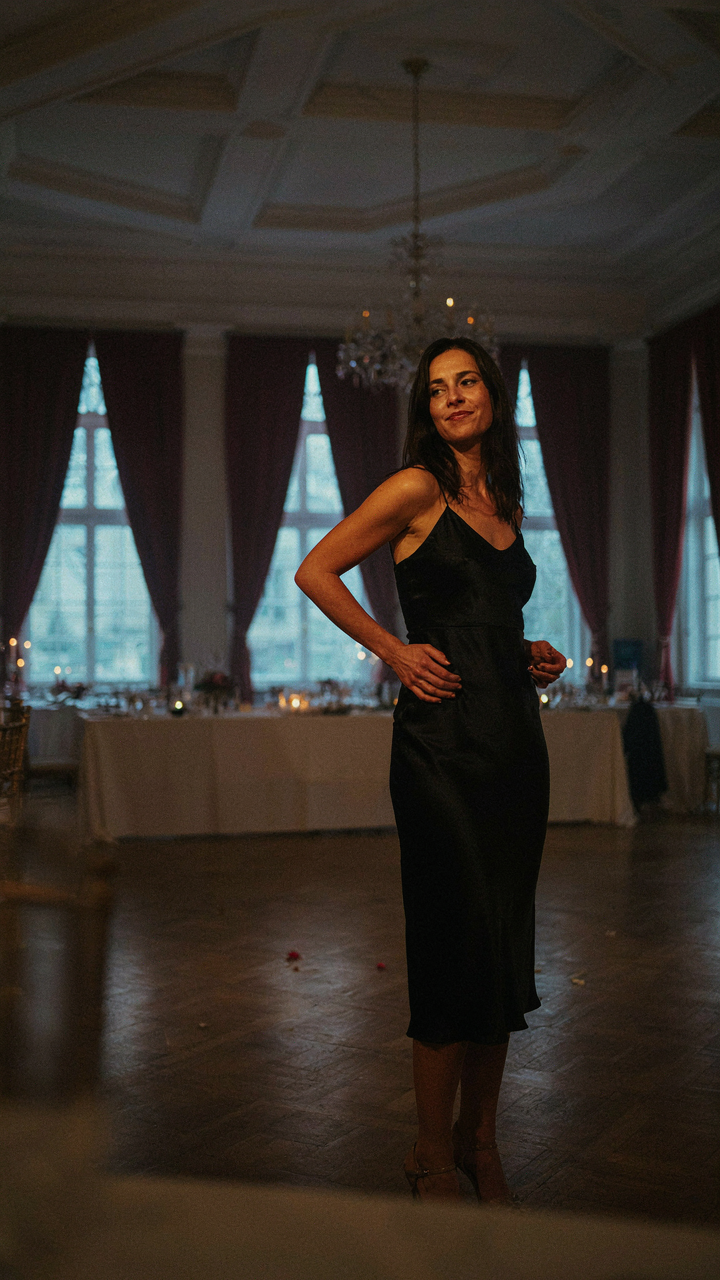 A woman stands alone in a grand hall, looking empowered and content.