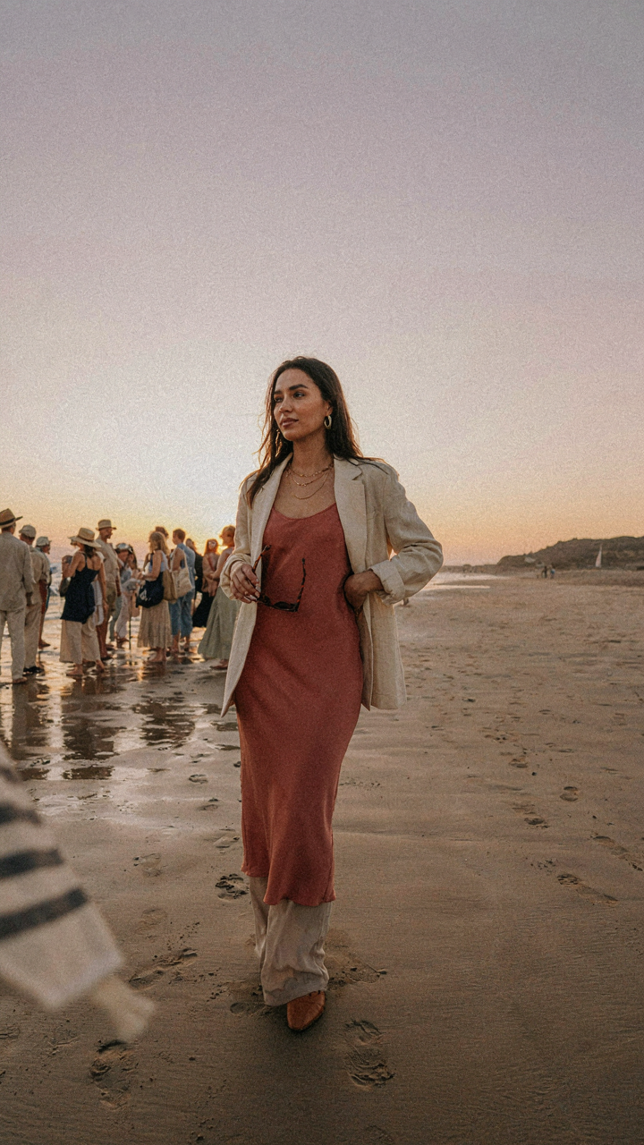 One person in a unique outfit stands out from a crowd on a beach.