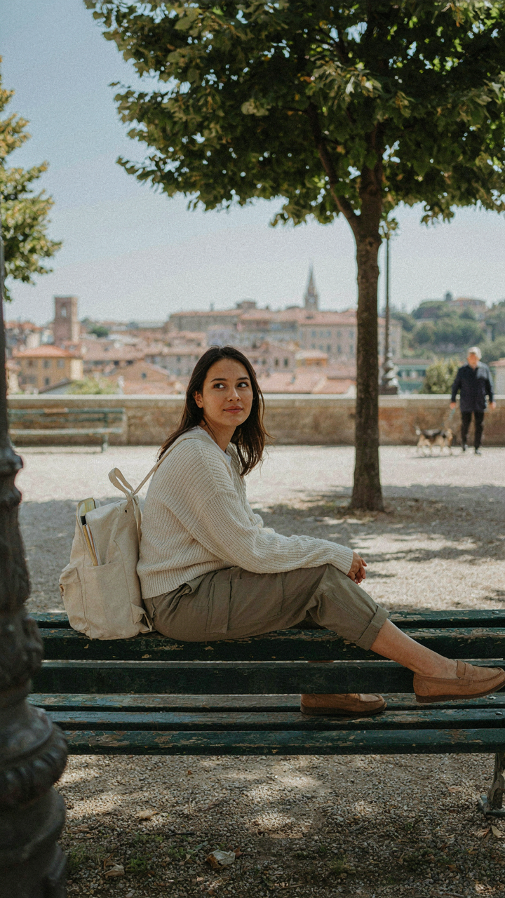 A person sits on a park bench, enjoying a city view, dressed in versatile layers.