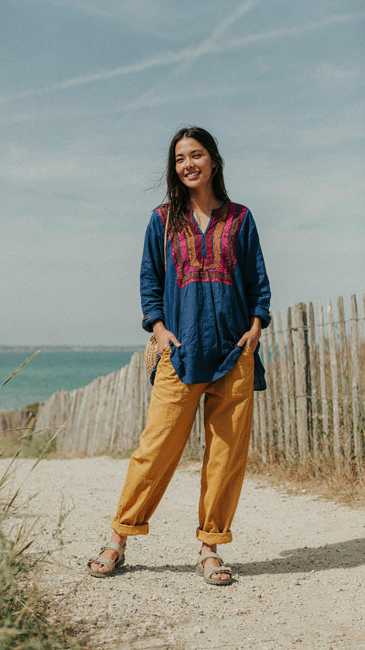A solo traveler in a bold outfit, smiling confidently against a natural backdrop.