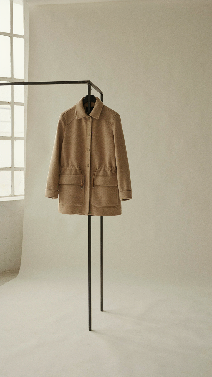 A versatile wool blend jacket hanging on a minimalist clothing rack.
