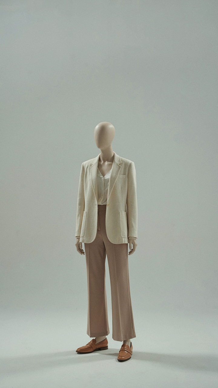 A perfectly styled single outfit stands on a mannequin in a minimalist space.
