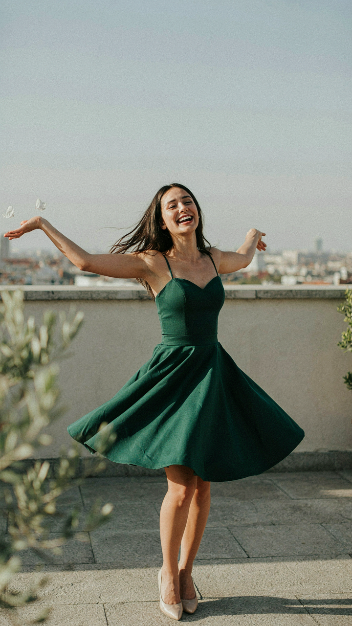 Woman laughing and dancing freely in a fit and flare cocktail dress.