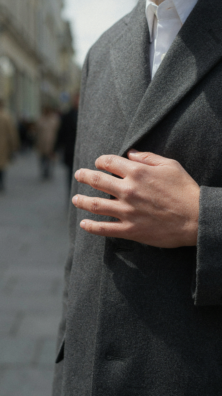A hand rests on the lapel of a structured blazer, showing its stability.