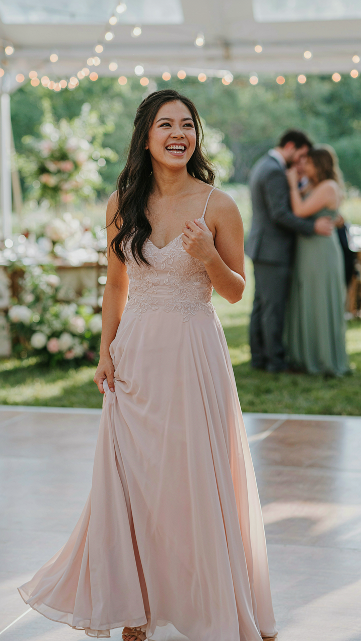 A woman on a dance floor, happy and comfortable in a flowing wedding guest dress.