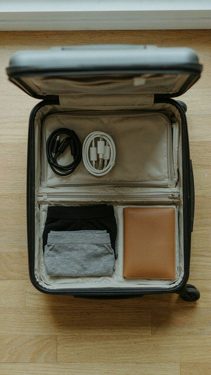 An open suitcase shows duplicate essential items like charging cables and underwear, for redundancy.