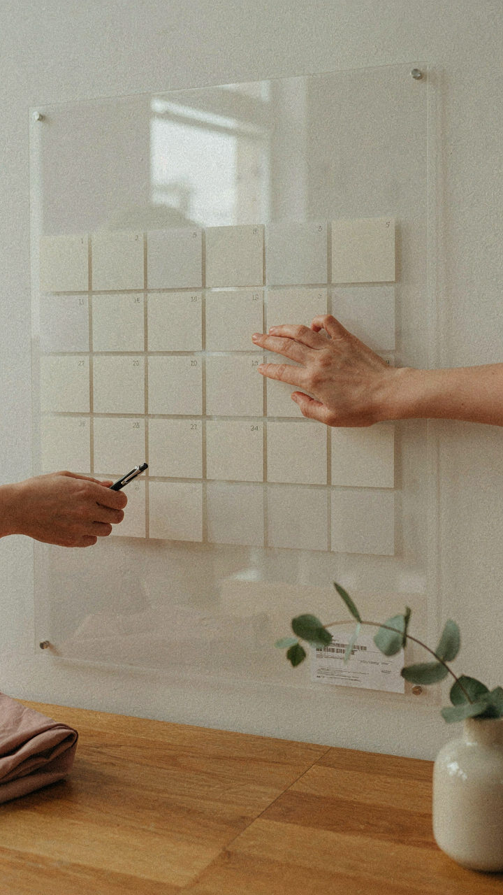 A hand points to dates on a calendar, planning to rent a wedding guest dress.