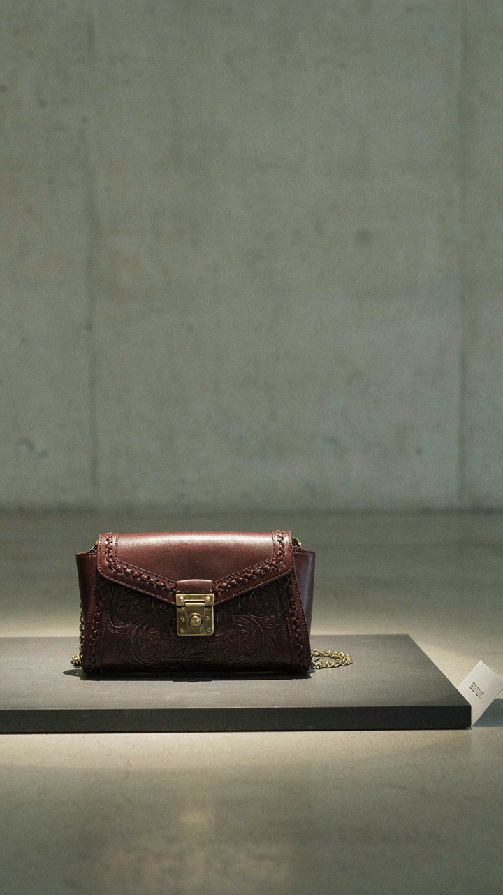 A unique designer clutch is spotlighted in a minimalist gallery setting.