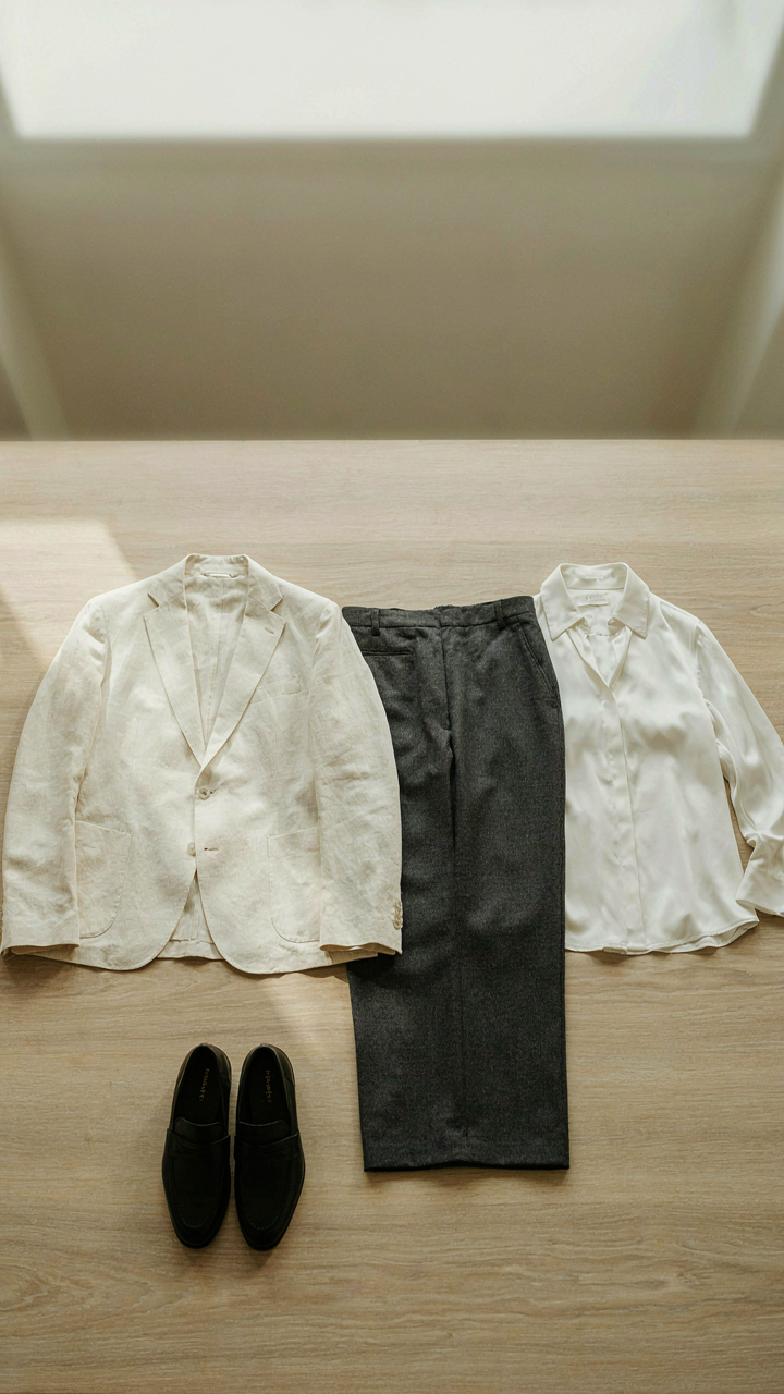 A minimalist wardrobe capsule with a cream blazer, charcoal pants, and loafers.