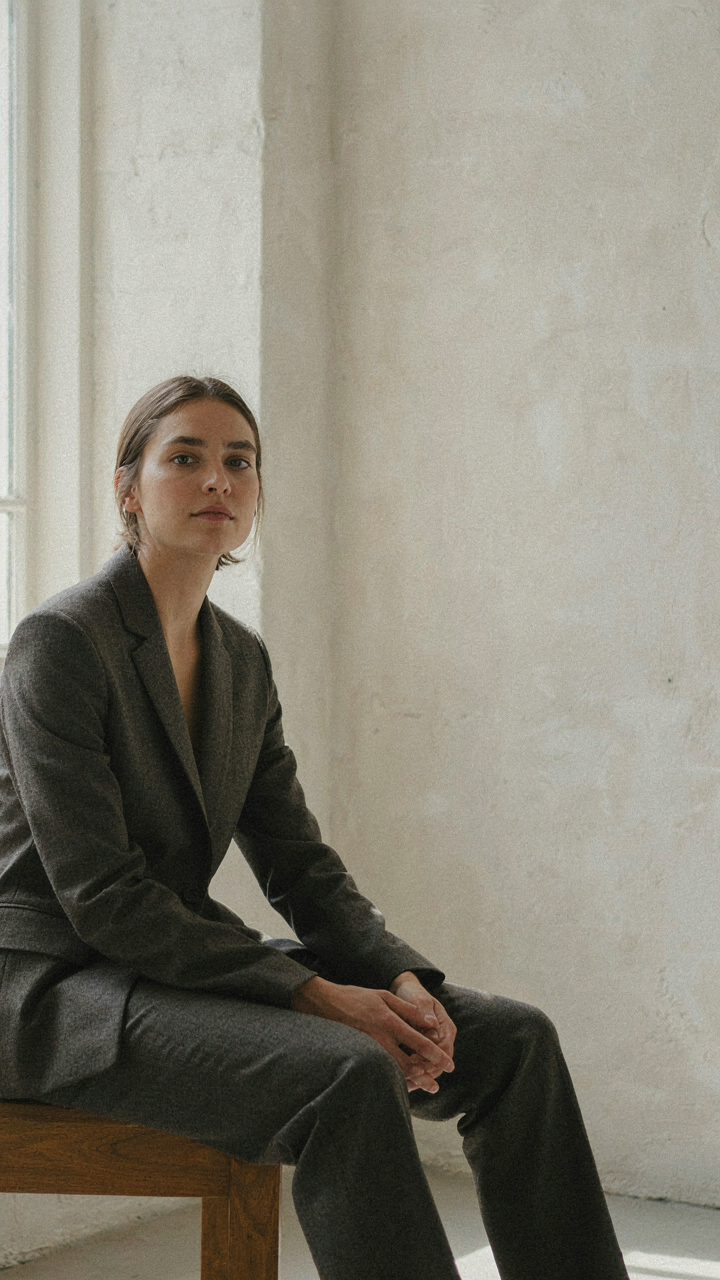 A person sits comfortably in a well-fitting wool blend wedding guest pantsuit.