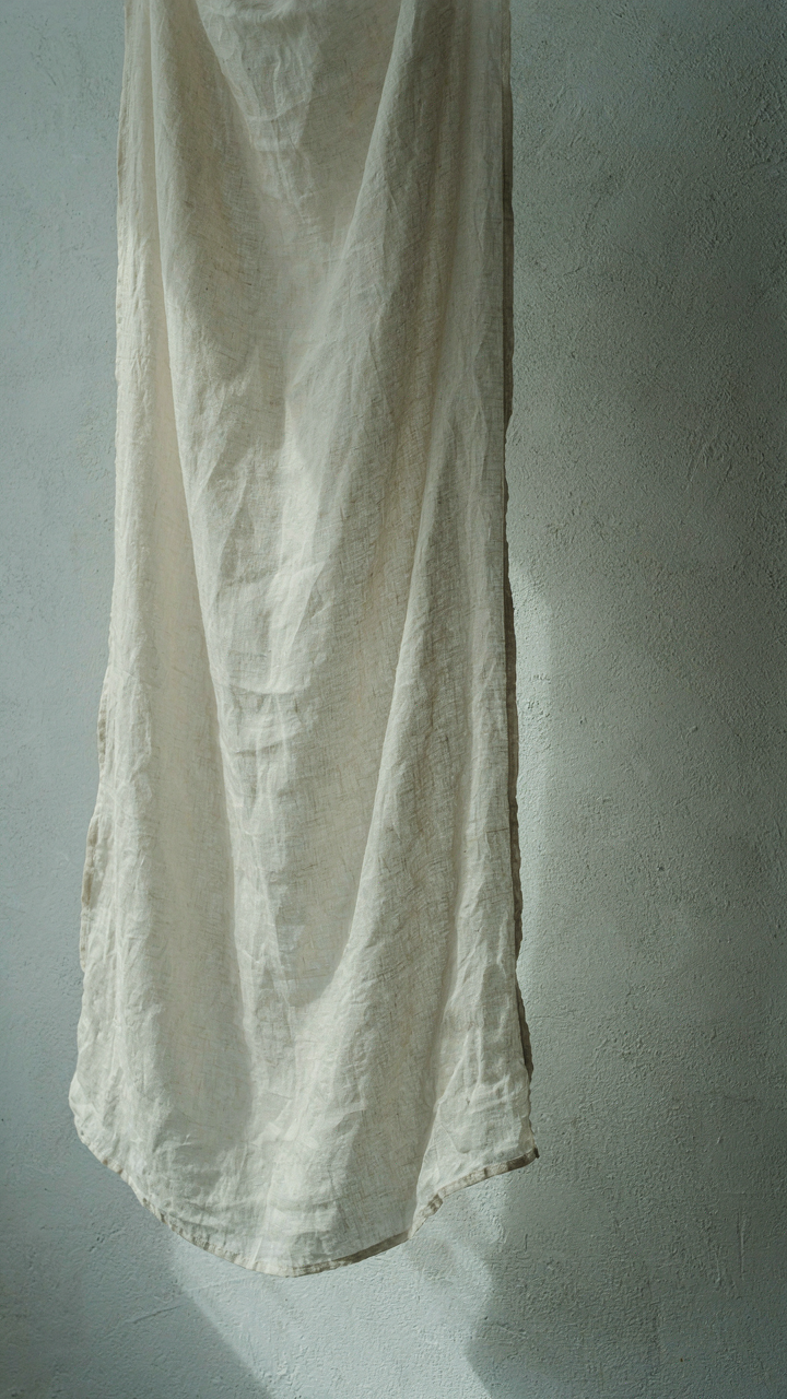 A close up view of a sheer fabric casting a faint shadow on a wall.