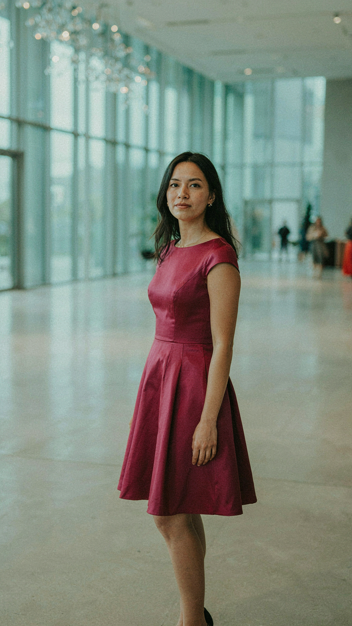 Woman in a magenta short satin cocktail dress in a modern event hall.