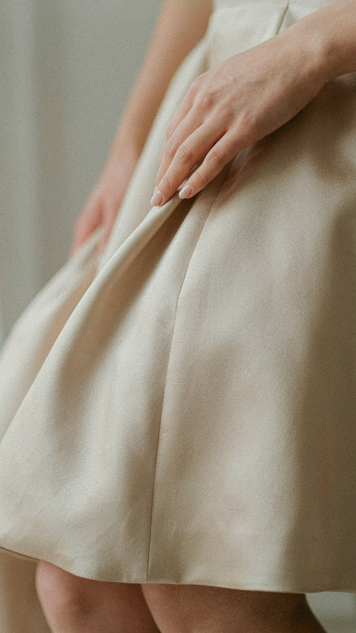 Close-up of luxurious silk fabric of a formal dress with a hand touching it.