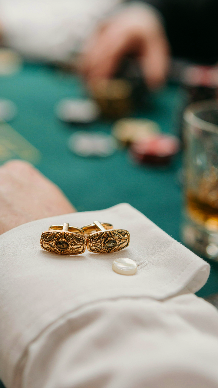 Gold cufflinks rest on a white shirt cuff, like a move in a game.