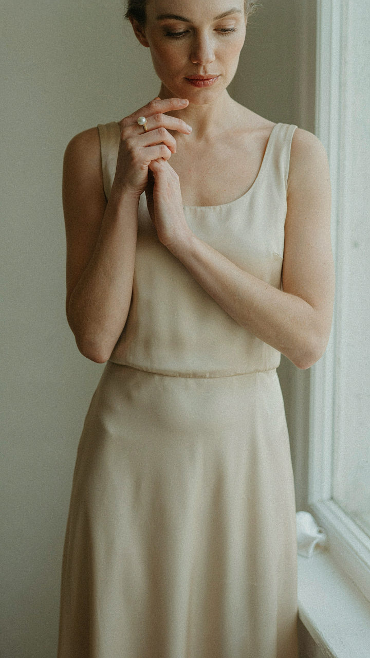 A single pearl ring is the only jewelry on a woman wearing a cocktail dress.