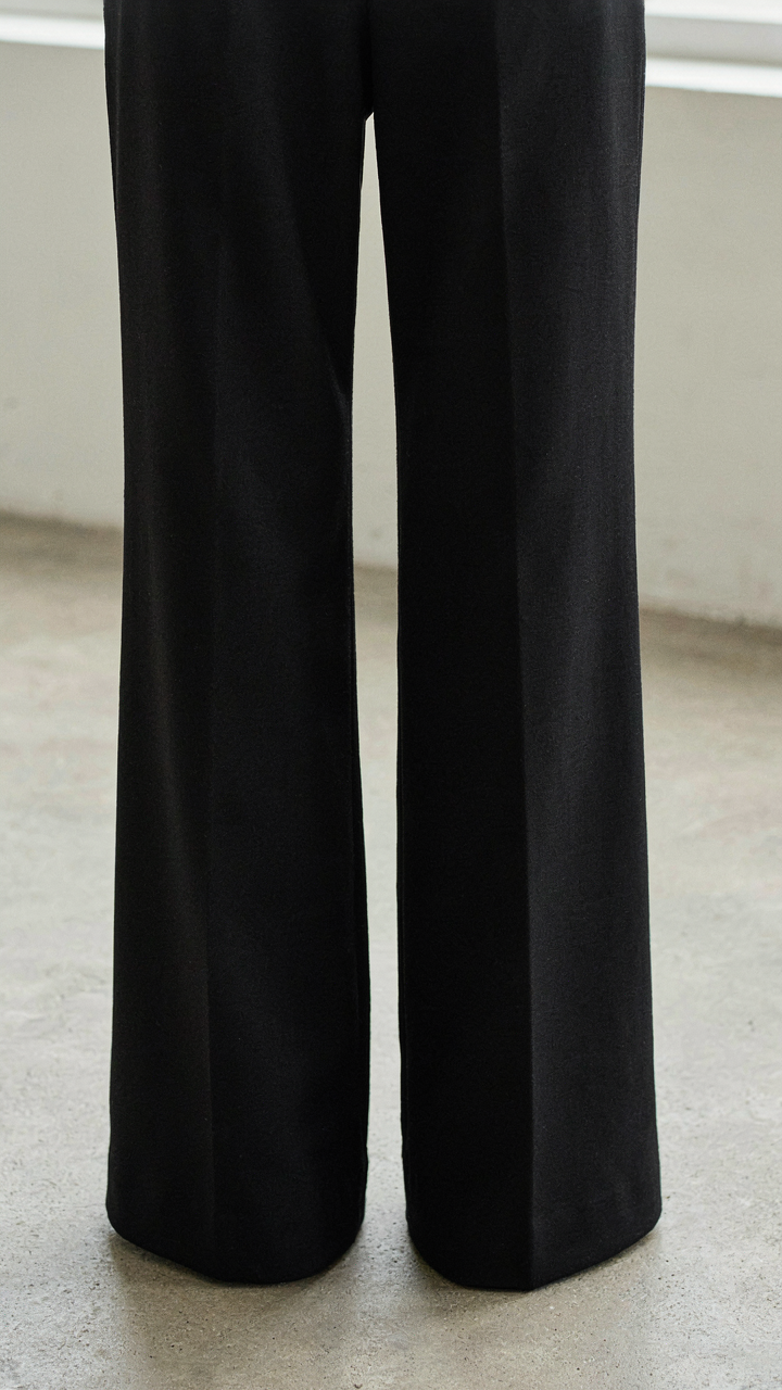 Close-up of precise vertical seams on a black wide leg jumpsuit.