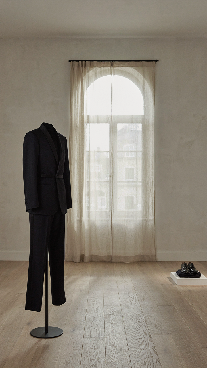 A perfectly tailored tuxedo jumpsuit displayed in a minimalist gallery.