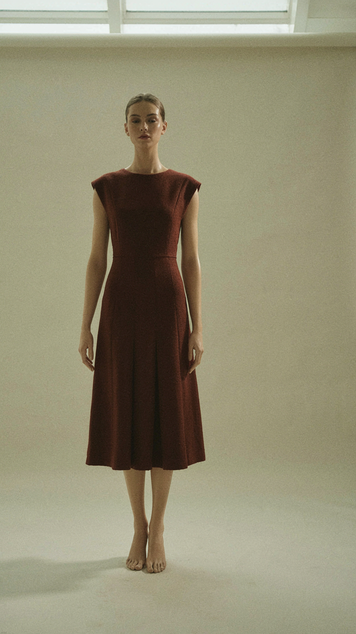 A mannequin wears a structured architectural dress with a defined waist.