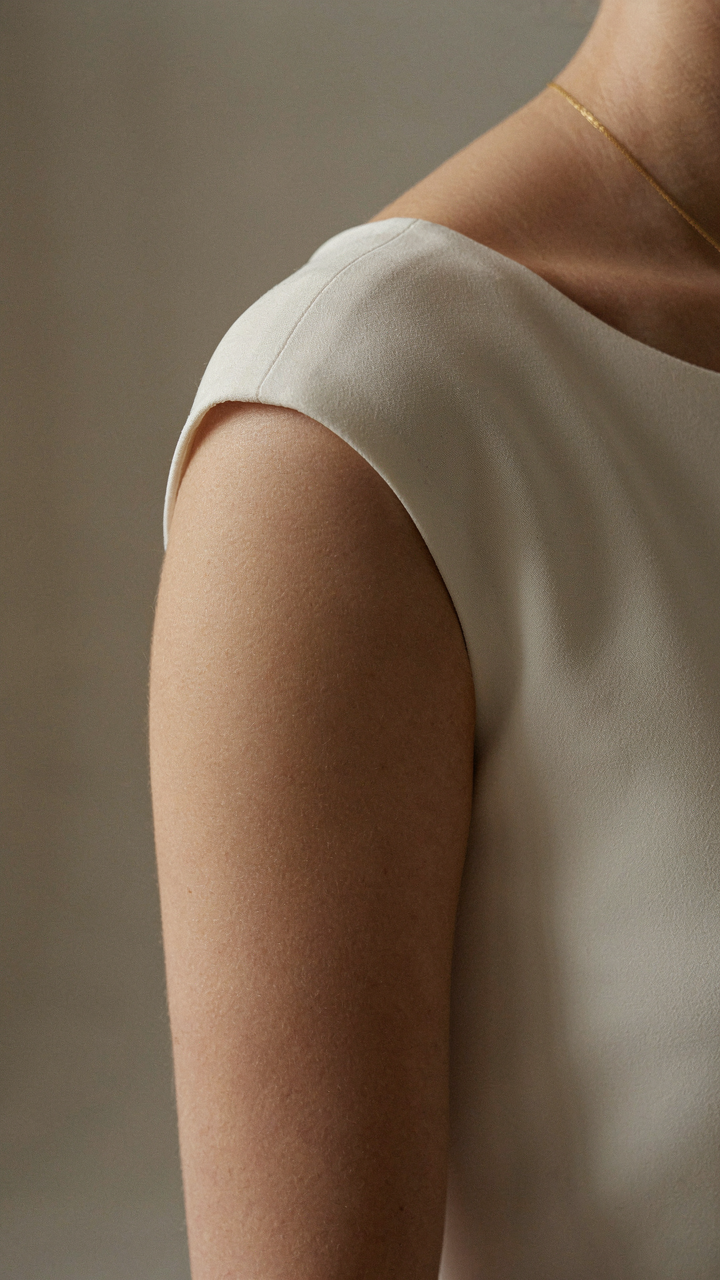 A woman's shoulder in a structured cap sleeve dress, showing the sleeve's clear edge.