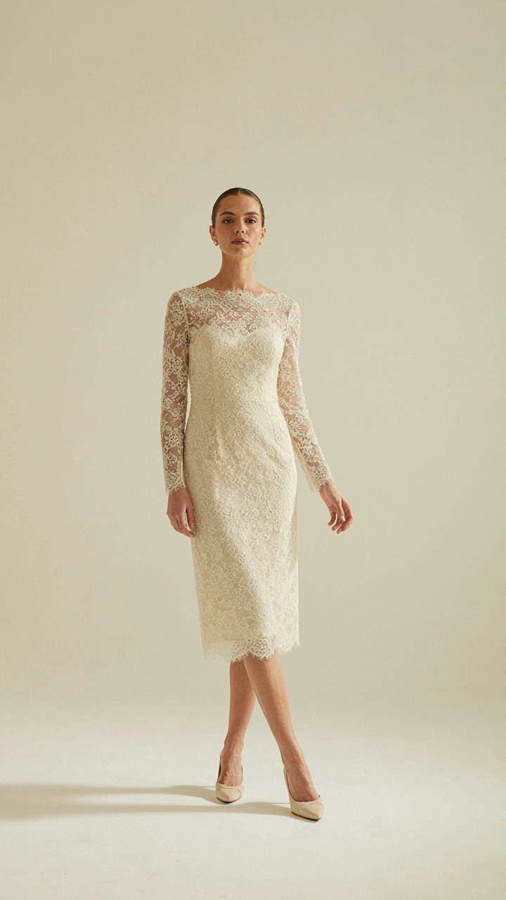 Woman standing with perfect posture, her lace cocktail dress draping flawlessly.