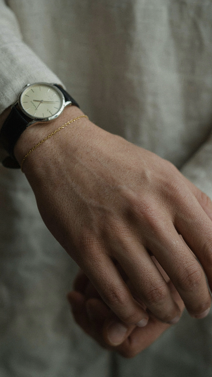 A close-up shows a person's wrist adorned with a subtle watch and bracelet.