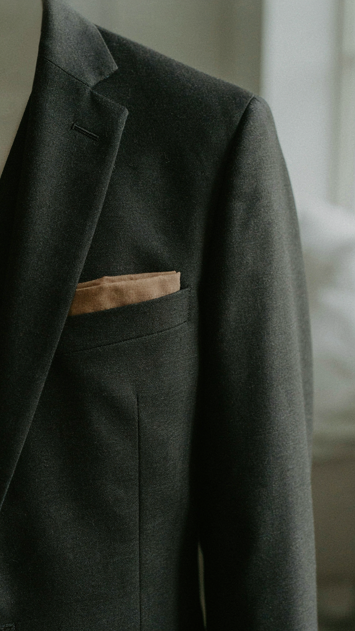 A dark blazer sleeve has a muted pocket square.