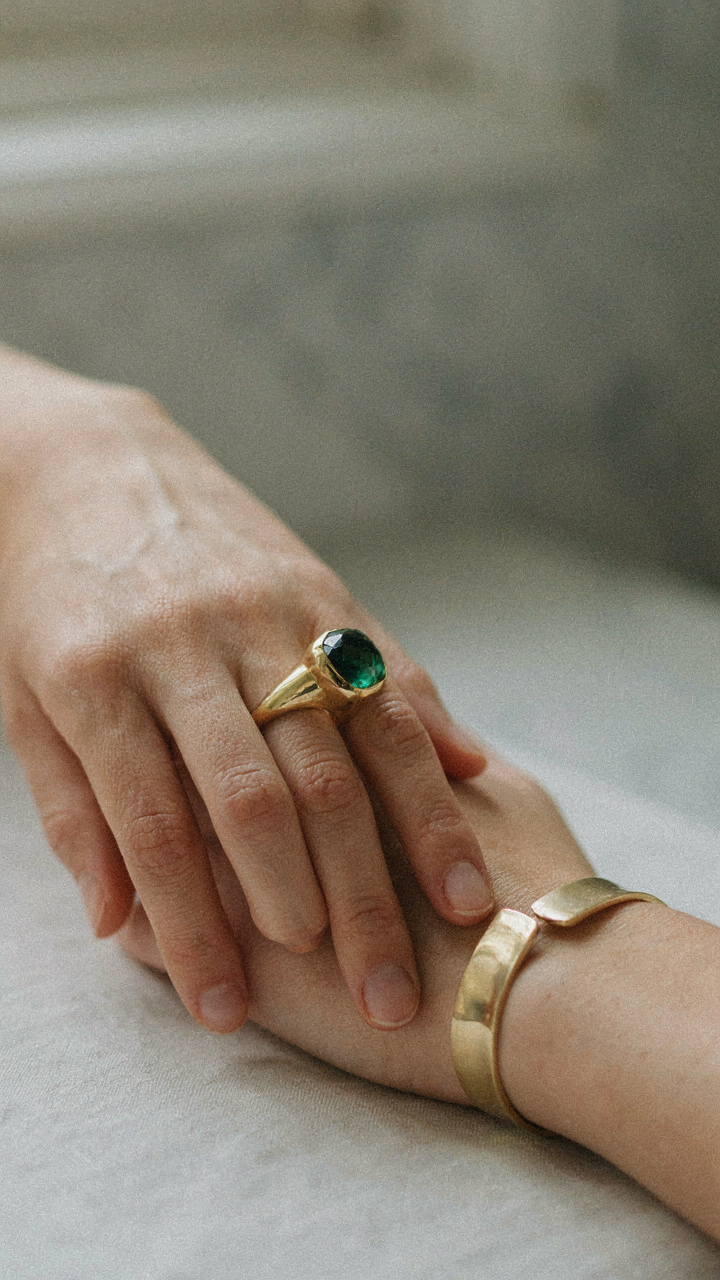 Hand wearing an oversized cocktail ring and a structured cuff bracelet.