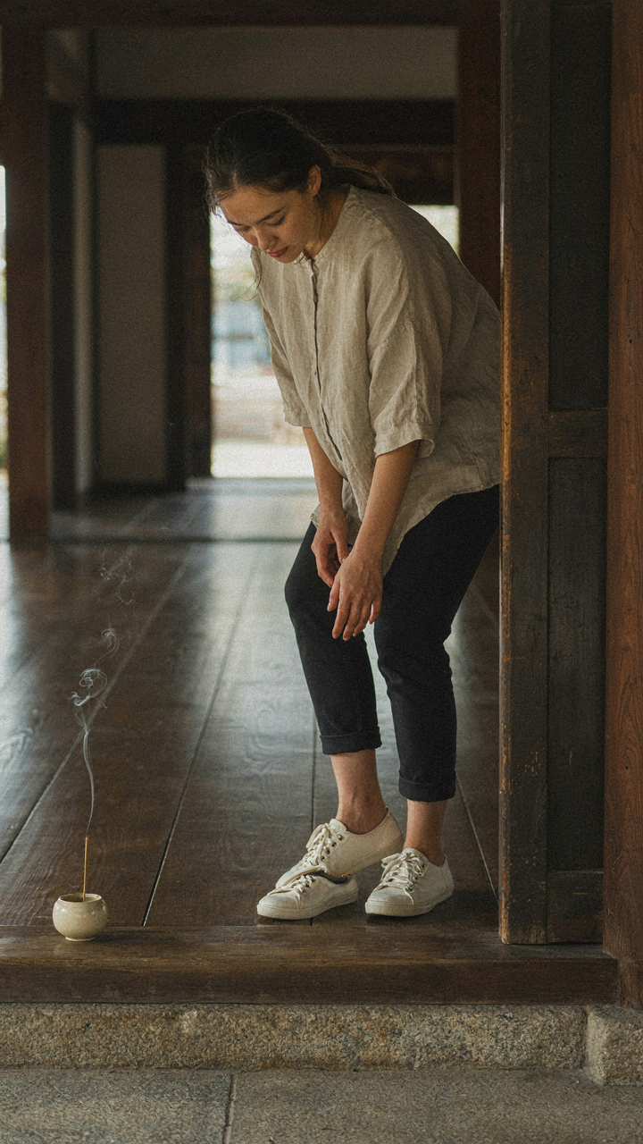 A person quickly removes minimalist sneakers at a temple entrance.