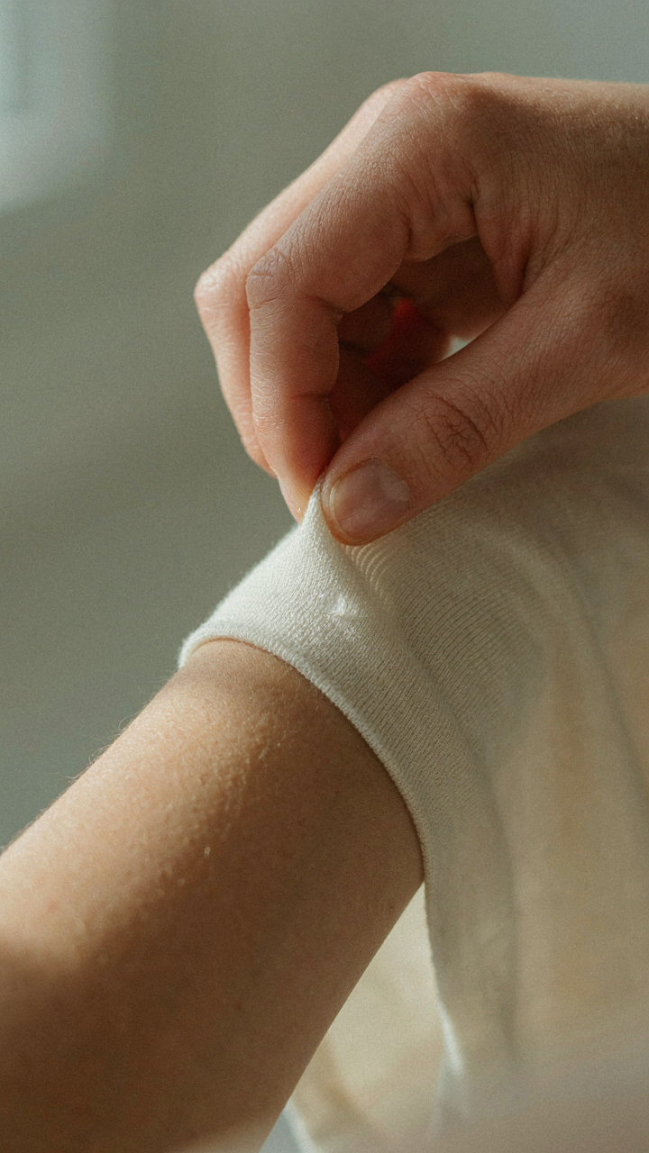 A woman's hand demonstrating the thinness of a merino wool base layer against her skin.