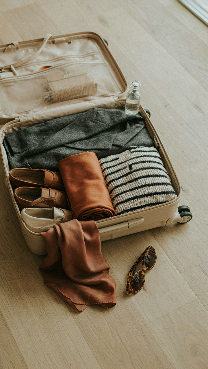 An open suitcase packed with a few versatile cocktail capsule wardrobe items.