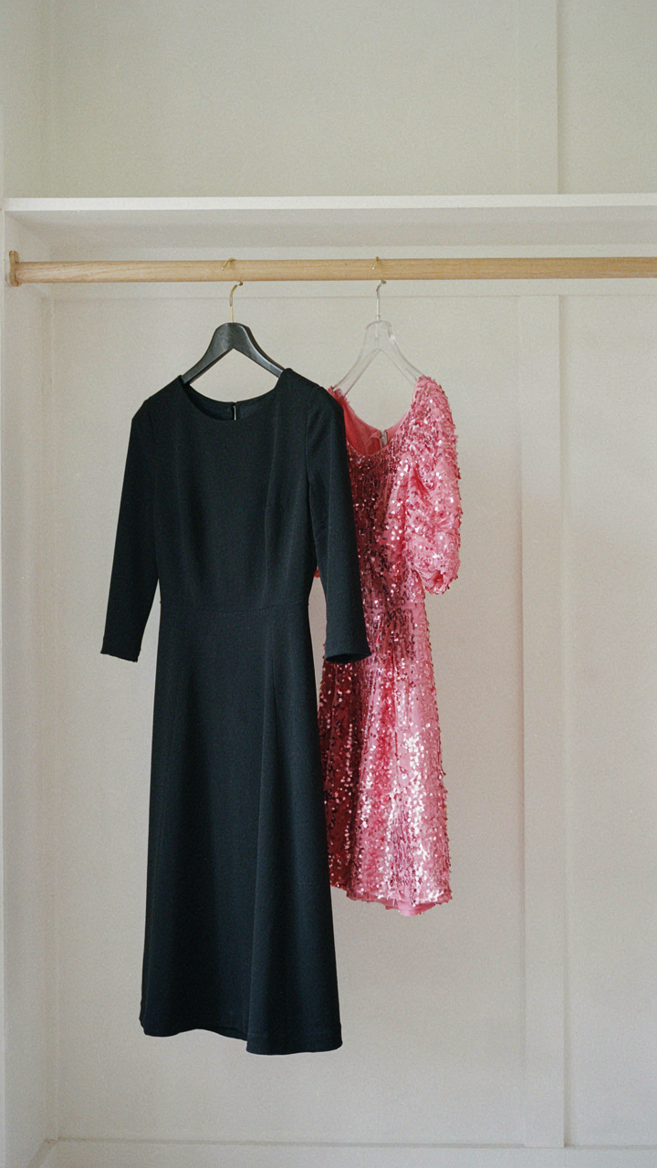 A classic black A-line dress hangs next to a dated, brightly colored trend dress.