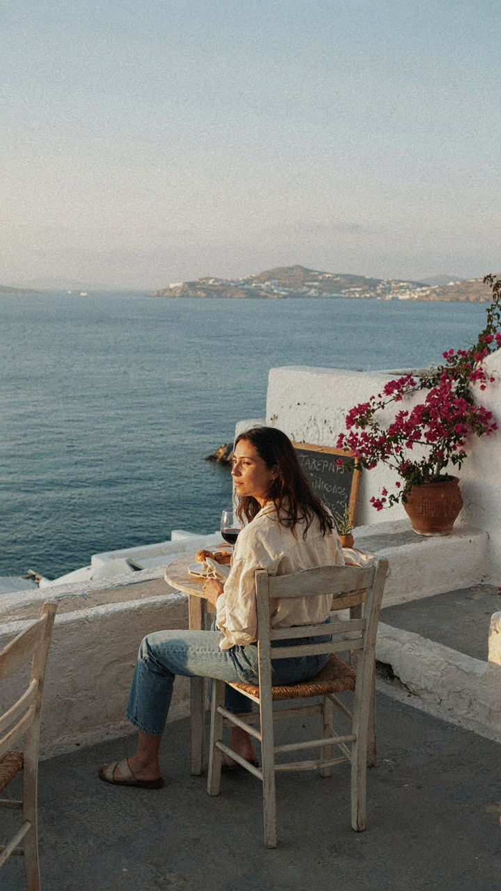 A person relaxing at a Greek taverna, enjoying the view of the sea.