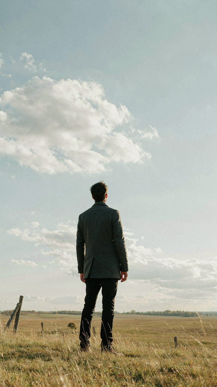 A lone figure stands confidently at the edge of a vast landscape.